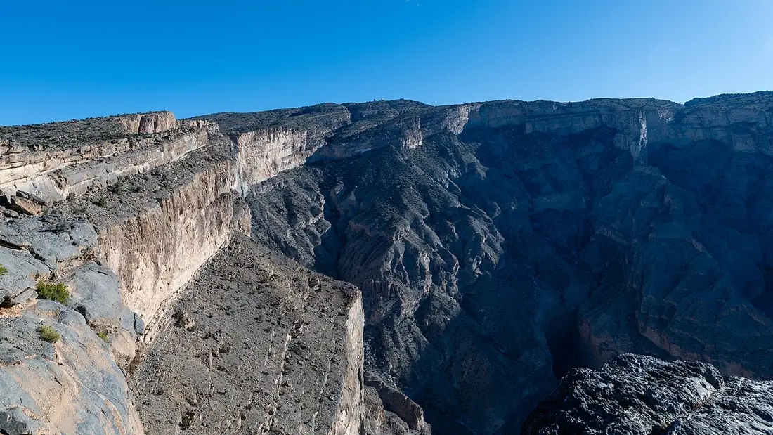 Le profonde pareti del canyon di Jebel Shams sotto un cielo azzurro.