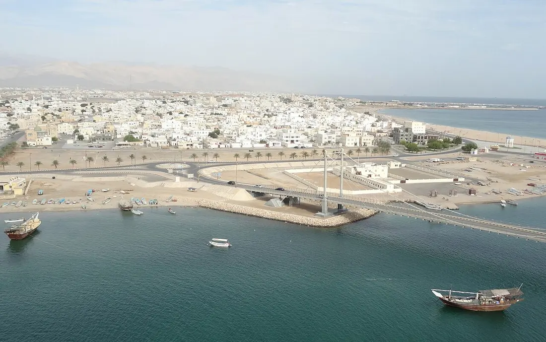 La laguna di Sur con dhow tradizionali, il ponte e gli edifici bianchi della città.